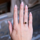 Chocolate brown diamond cluster tre-foil engagement ring worn on hand with gold band.