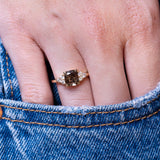 Chocolate brown diamond cluster tre-foil engagement ring worn on hand with denim pocket styling.