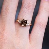 Chocolate brown diamond cluster tre-foil engagement ring with diamond side stones worn on finger.