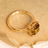 Golden-ochre chrysoberyl ring showcasing a step-cut gemstone in a refined yellow gold solitaire design.