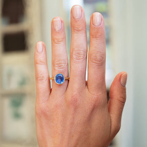 Cornflower blue sapphire solitaire ring worn on hand with natural manicure.