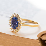 Cornflower blue sapphire and diamond cluster engagement ring with oval sapphire and brilliant-cut diamond halo.