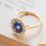 Cornflower blue sapphire and diamond cluster engagement ring in polished yellow gold.