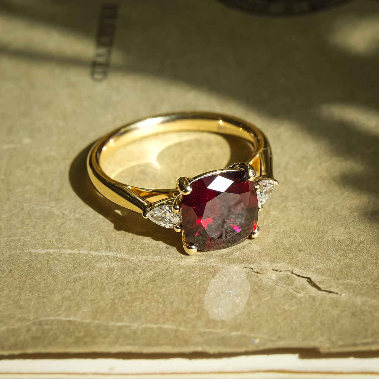 Cushion cut 3ct ruby with diamond three stone engagement ring in yellow gold