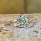 Cushion-cut fancy yellow diamond cluster ring surrounded by white diamonds in yellow gold.