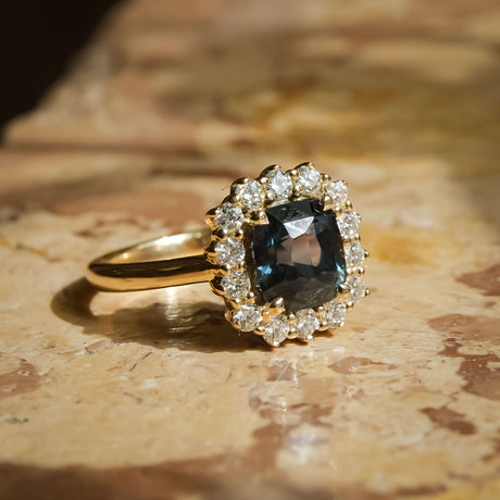 Cushion cut green sapphire and diamond cluster engagement ring in yellow gold band