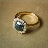 Cushion cut green sapphire and diamond cluster engagement ring in classic yellow gold setting