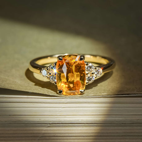 Cushion cut orange sapphire ring with diamond trefoil cluster setting