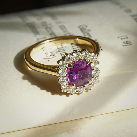 Cushion cut pink sapphire and diamond cluster halo engagement ring in yellow gold setting