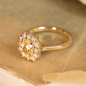 Yellow sapphire and diamond cluster ring with a vibrant cushion-cut sapphire and dazzling diamond halo set in yellow gold.