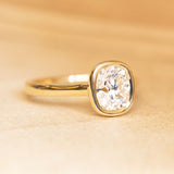Cushion old-cut diamond solitaire engagement ring in a yellow gold rub-over setting.