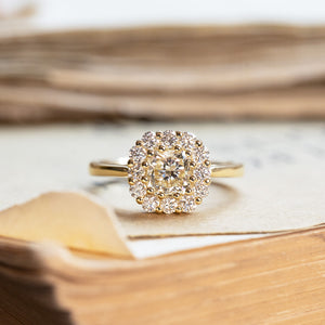 Diamond cluster engagement ring with round brilliant centre diamond and diamond halo setting.