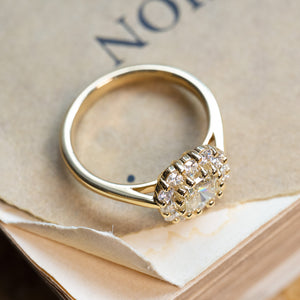 Diamond cluster engagement ring with raised gallery setting and polished gold band.