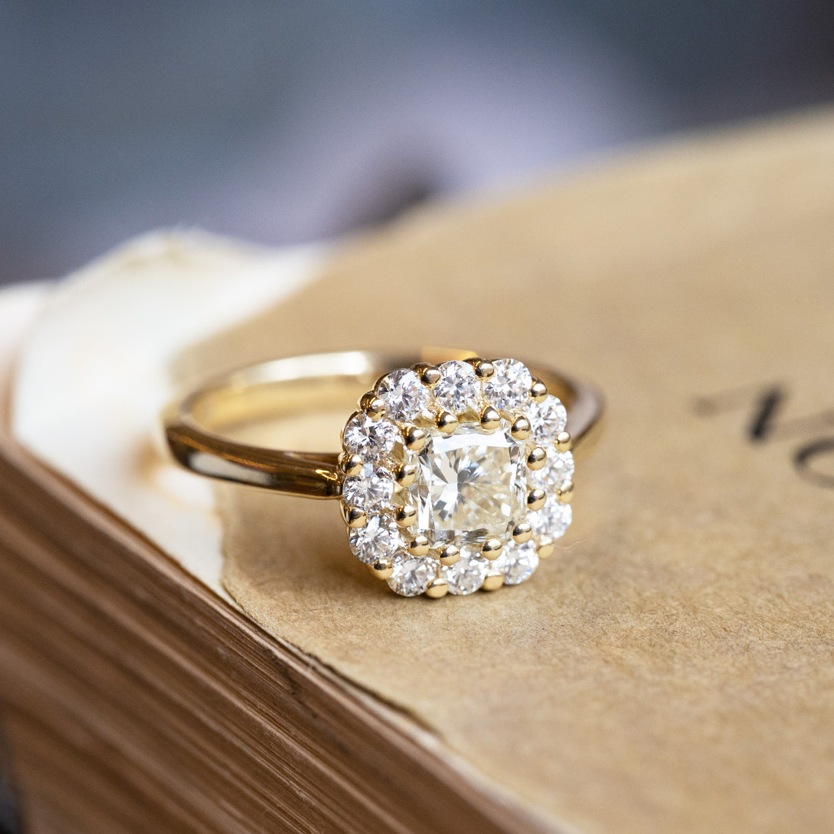 Diamond cluster engagement ring with round brilliant centre stone and diamond surround.