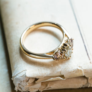 Diamond three-stone engagement ring with diamond side stones and polished gold band.