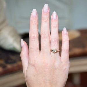 Diamond three-stone engagement ring worn on hand.