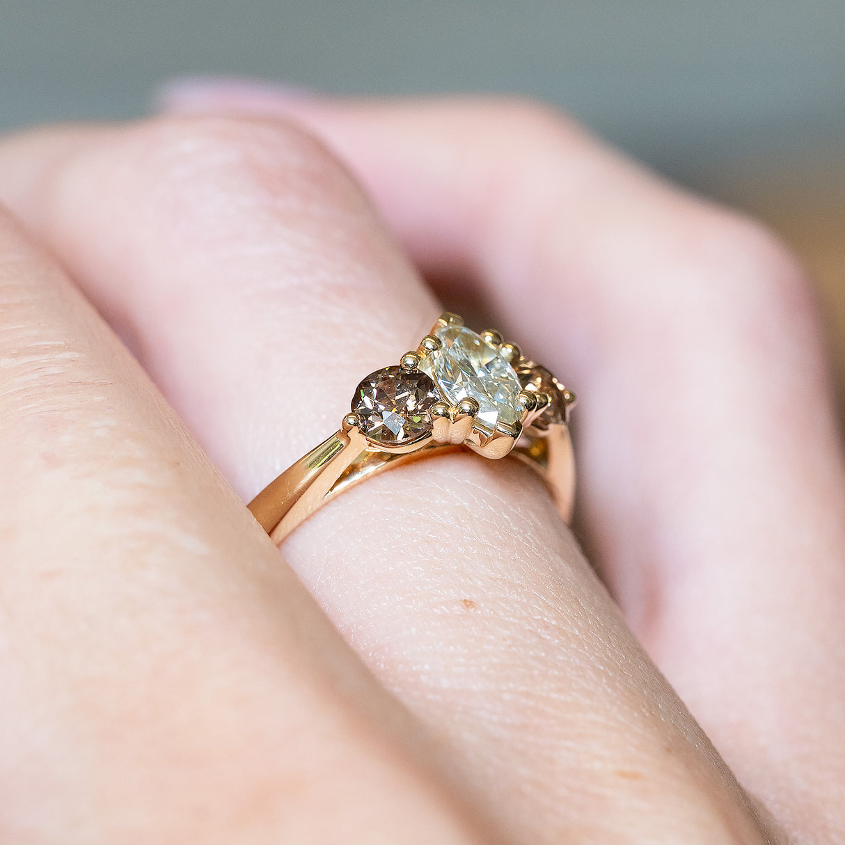 Diamond three-stone engagement ring with marquise-cut diamond and diamond accents on gold band.