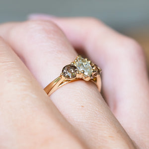 Diamond three-stone engagement ring with marquise-cut diamond and diamond accents on gold band.