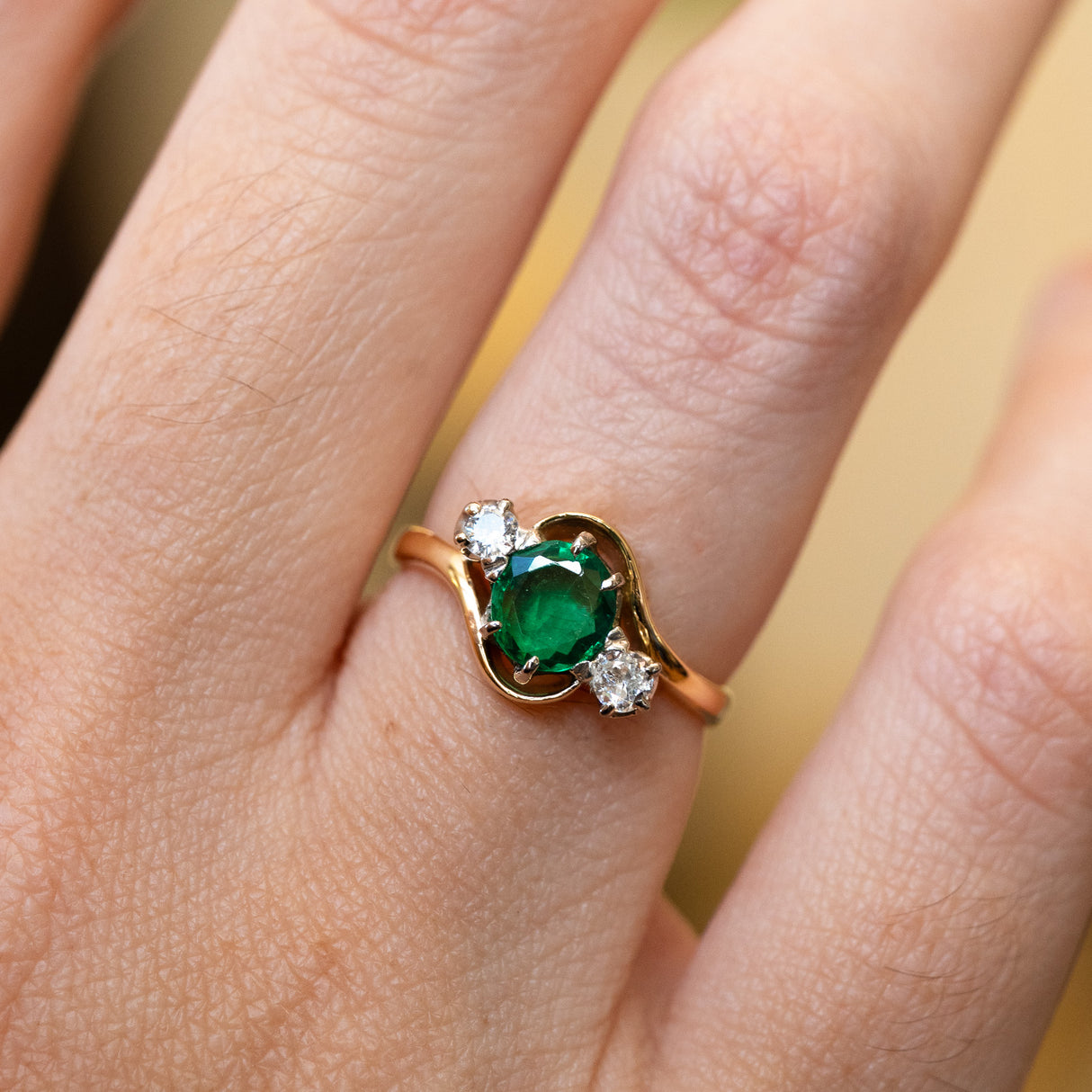 Emerald ring with diamond side stones showing rich green tone and soft sparkle.
