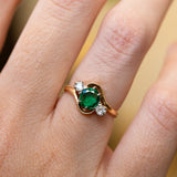 Emerald ring with diamond side stones showing rich green tone and soft sparkle.