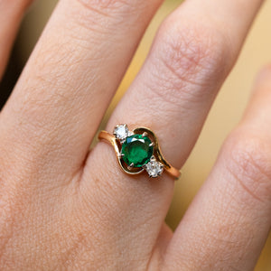 Emerald ring with diamond side stones showing rich green tone and soft sparkle.