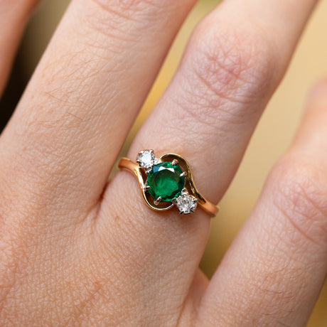 Emerald ring with diamond side stones showing rich green tone and soft sparkle.