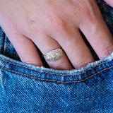 Edwardian diamond cluster ring worn with denim showing soft antique sparkle.