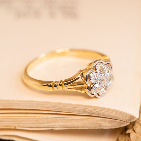 Edwardian diamond cluster ring with sparkling old-cut diamonds forming a classic daisy motif in a refined yellow and white gold setting.