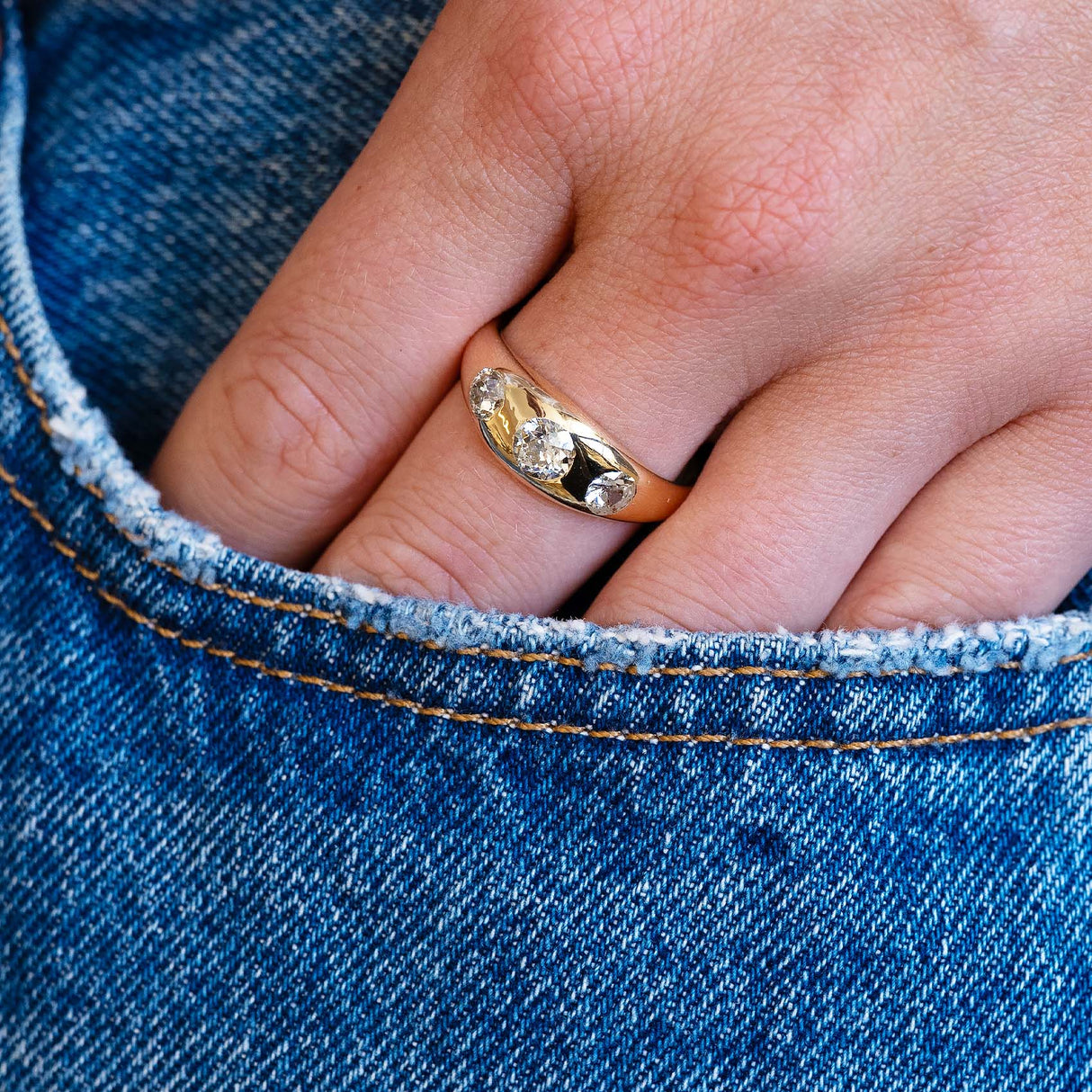 Edwardian diamond gypsy ring worn on hand with denim pocket detail.