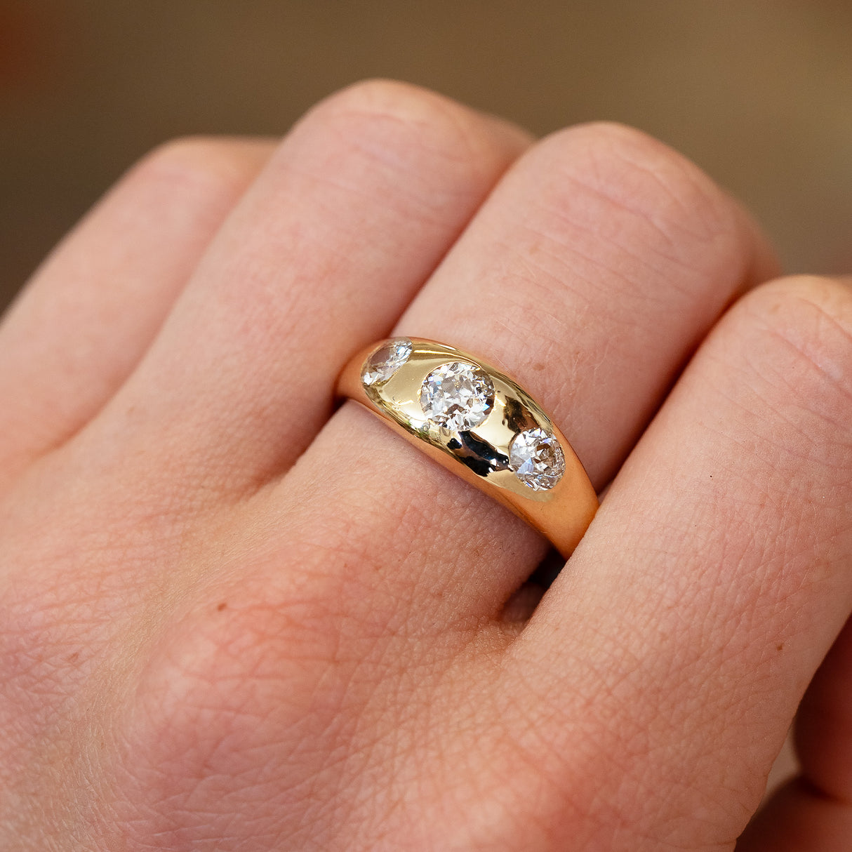 Gold gypsy ring with three old cut diamonds showing soft sparkle and smooth curved surface.