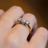 Diamond ring highlighting three stones with gentle light reflections.
