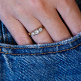Edwardian diamond three stone ring worn on hand with denim pocket detail.