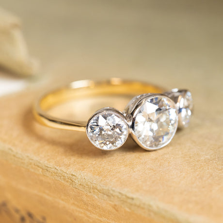 Antique Edwardian three-stone ring with old-cut diamonds and a yellow gold band.