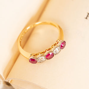 Edwardian ruby and old-cut diamond ring showcasing five graduating gemstones set across a refined yellow gold band.