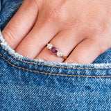 Ruby and diamond ring worn on hand with denim pocket detail.