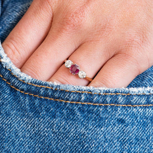 Ruby and diamond ring worn on hand with denim pocket detail.