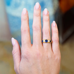 Antique five stone ring worn on hand with blue sapphire and old mine cut diamonds.