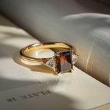 emerald cut brown diamond three stone ring with diamond side stones in yellow gold
