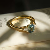 Emerald cut green sapphire with diamond three stone engagement ring in yellow gold