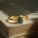 Emerald cut green sapphire and diamond three stone engagement ring in yellow gold band