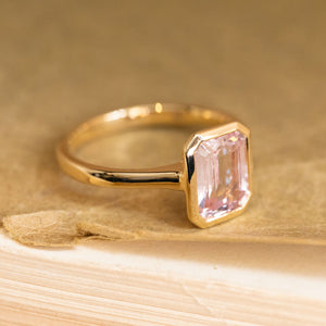 Emerald-cut pink sapphire solitaire ring showcasing a delicate pastel pink sapphire with clean, elegant lines in yellow gold.
