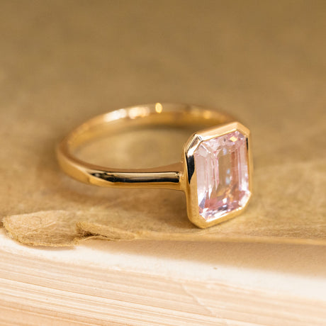 Emerald-cut pink sapphire solitaire ring showcasing a delicate pastel pink sapphire with clean, elegant lines in yellow gold.