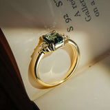 Emerald cut teal sapphire ring with diamond trefoil cluster setting