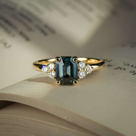 Emerald cut teal sapphire ring with diamond trefoil cluster setting