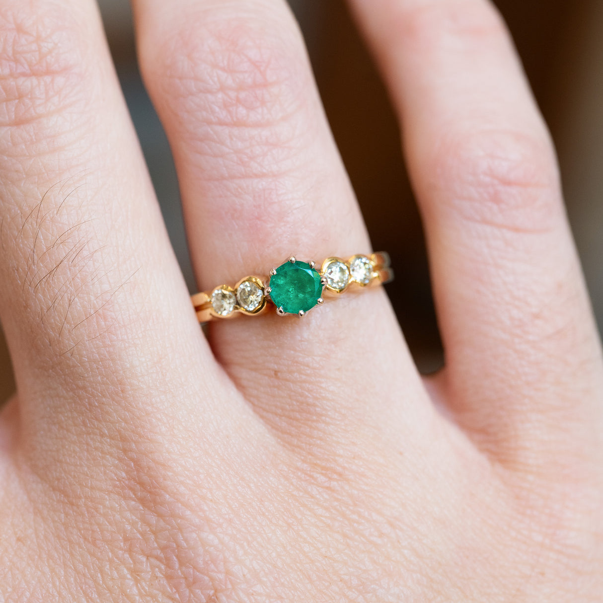 Emerald and diamond five stone ring close detail showing stone arrangement.