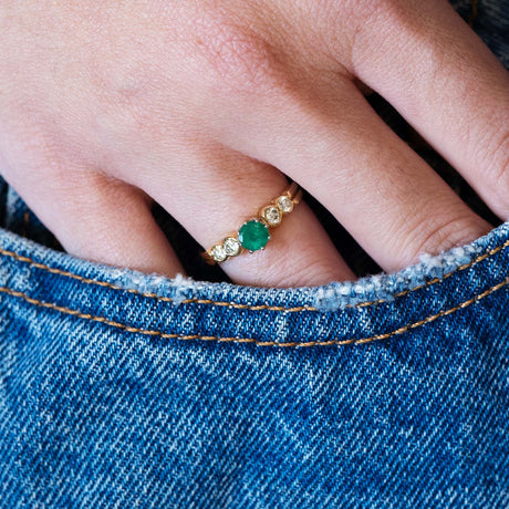 Vintage emerald five stone ring worn with a denim pocket detail.