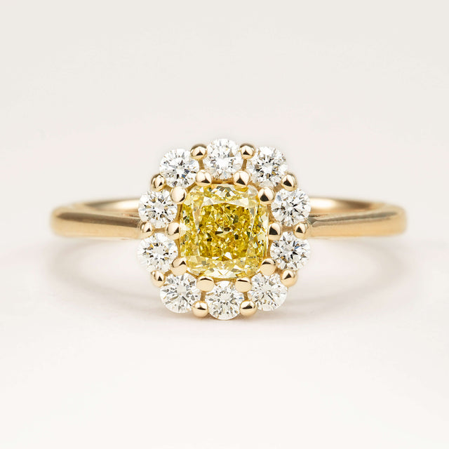 Fancy yellow cushion-cut yellow diamond cluster engagement ring in yellow gold.
