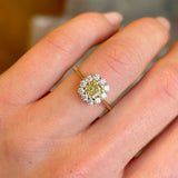 Fancy yellow cushion-cut diamond cluster engagement ring worn on hand.