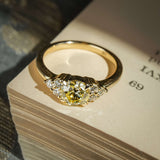 Fancy light yellow diamond ring with central stone and trefoil cluster of white diamonds