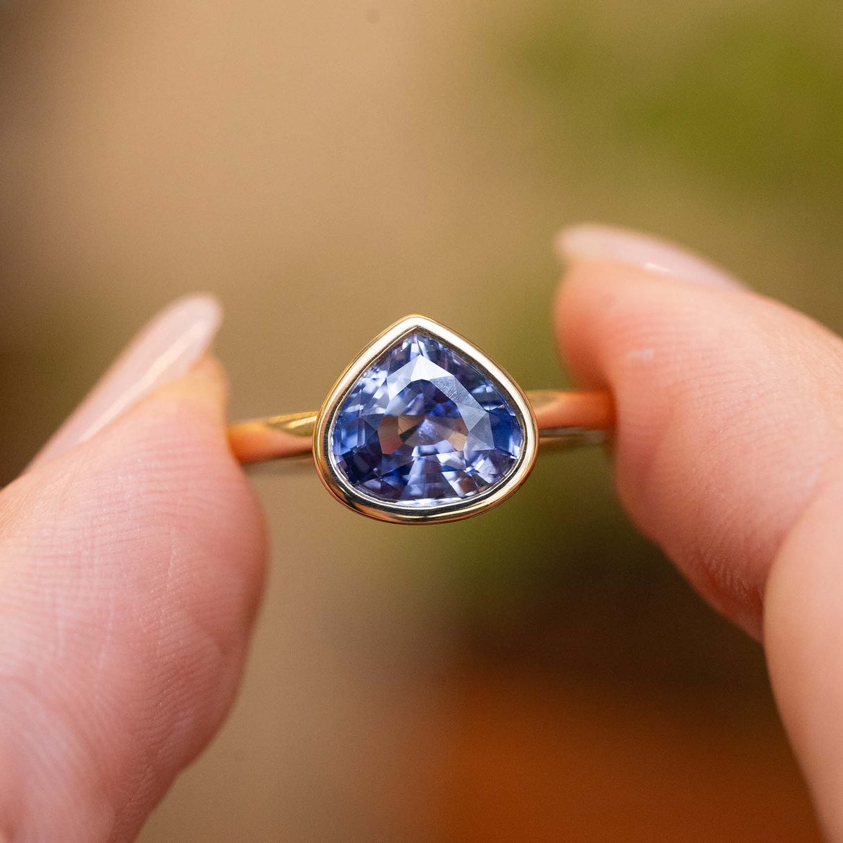 Close-up of an antique-inspired pear-cut blue sapphire solitaire ring in yellow gold.